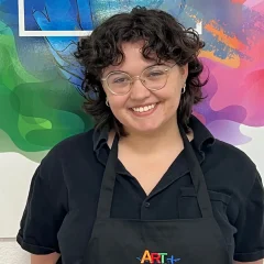 Professional portrait of art teacher with Art Plus Academy logo in the background at Southwest Austin location