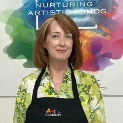 Professional portrait of art teacher with Art Plus Academy logo in the background at Southwest Austin location