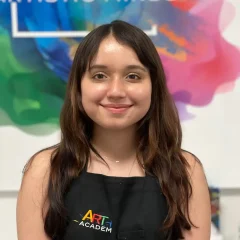 Professional portrait of art teacher with Art Plus Academy logo in the background at Southwest Austin location