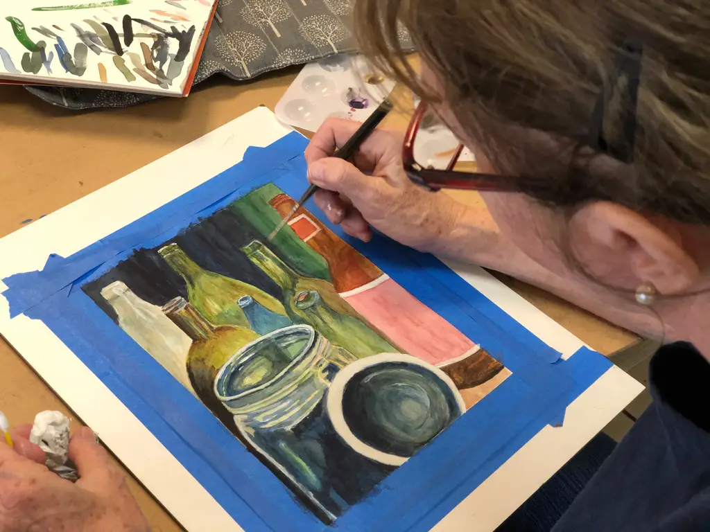 Elderly woman painting detailed bottles and jars with reflections during Art Class in Round Rock