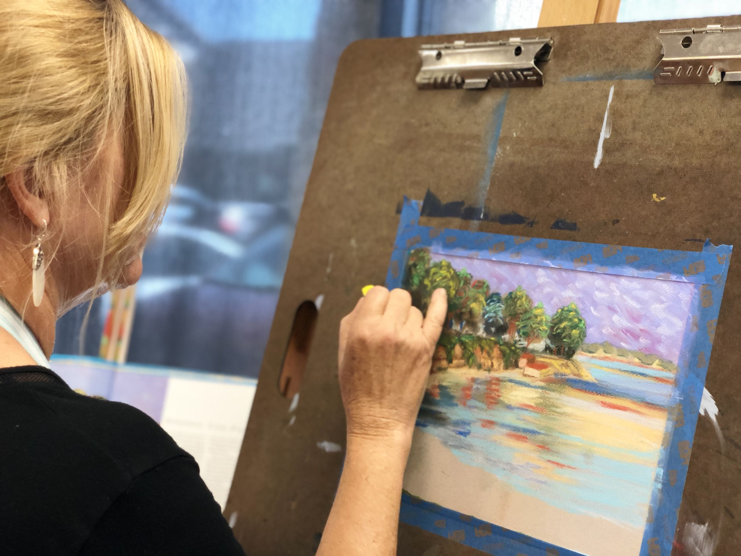 Adult woman painting a landscape during Art Class in Dripping Springs, focusing on natural scenery and color blending