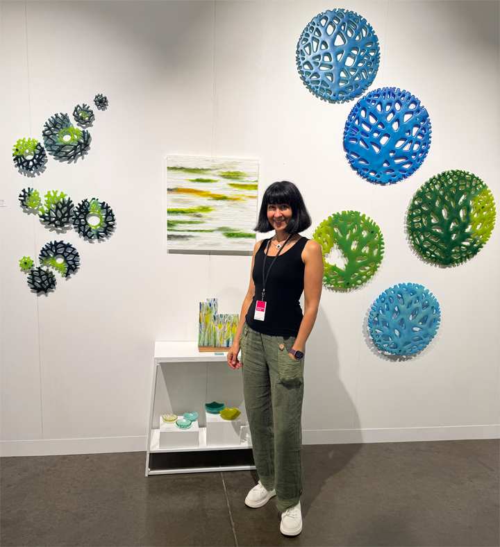 Student standing proudly in front of their artwork during an exhibition at Art Class in Oak Hill