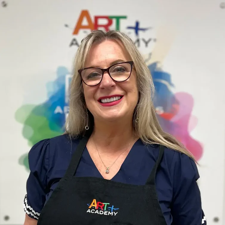 Professional portrait of art teacher with Art Plus Academy logo in the background at Southwest Austin location