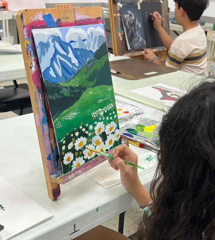 Young girl painting a mountain range with sunflowers and grassland during Art Class in Brushy Creek, showing strong landscape skills