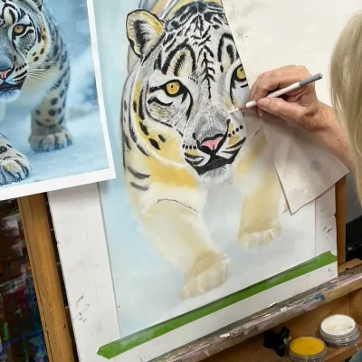 Elderly student coloring a white tiger walking through snow during Art Class in Oak Hill, focusing on contrast and realism